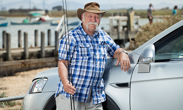 old man stnading beside car